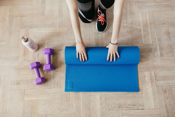 A neatly rolled up yoga mat on a wooden floor.